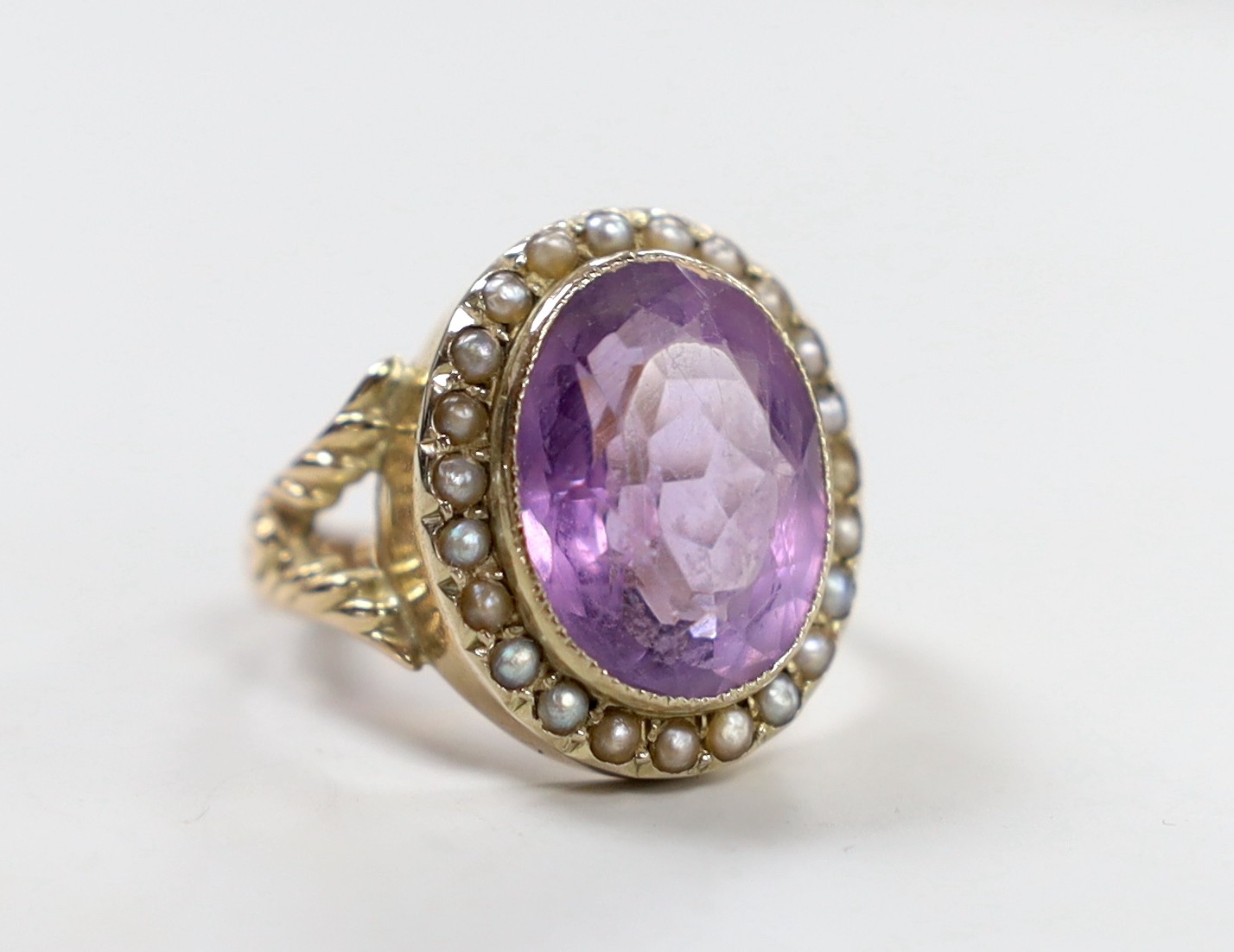 A Victorian style yellow metal, amethyst and seed pearl set oval dress ring, size N/O, gross weight 6.3 grams.